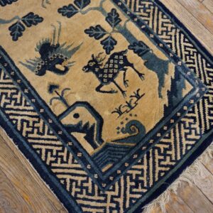 Tan and blue geometric rug with animal motifs rests on distressed, light wood flooring.