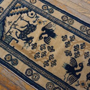 A low pile tan rug with navy blue deer and bird patterns lies diagonally across rustic wooden flooring.
