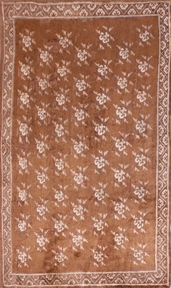 Brown rug with a low pile features repeated white floral medallions and patterned white borders.