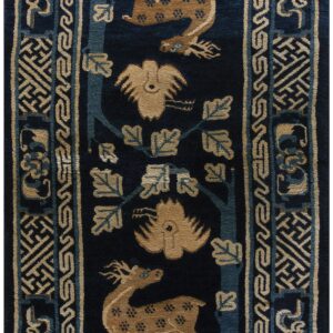A long navy blue rug runner featuring tan deer and stylized birds bordered by geometric key-fret patterns.