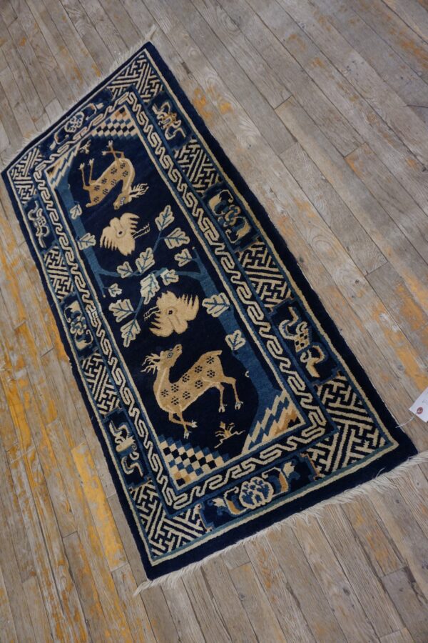 Navy blue and beige rug with animal motifs and geometric borders rests on aged wood planks.
