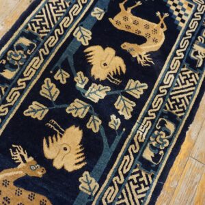 Navy blue runner with beige deer and stylized trees, framed by geometric borders on worn wood planks.