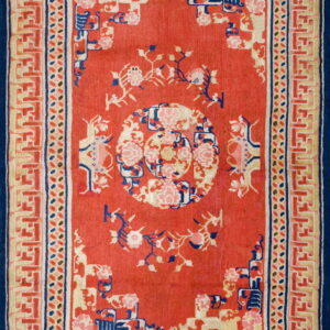 Red rug with a central medallion, peonies, and a complex blue and cream key-pattern border.