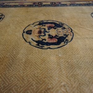 Tan rug with a subtle geometric field, dark blue medallions, and a detailed top border.