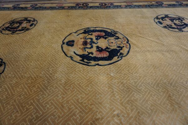 Tan rug with a subtle geometric field, dark blue medallions, and a detailed top border.