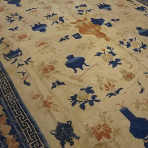 Cream rug with scattered dark blue and rust stylized motifs and a blue Greek key border.