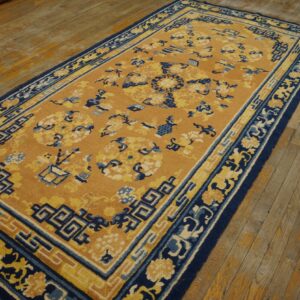 Mustard and navy runner rug with complex borders and scattered motifs rests on distressed wood planks.