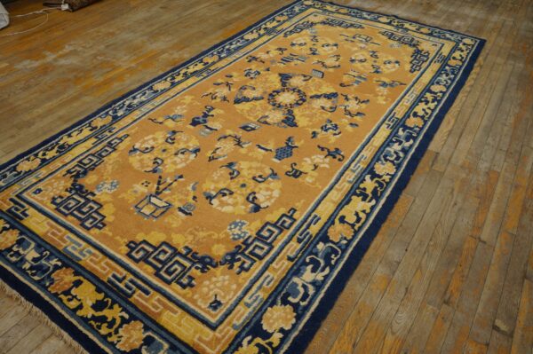 Mustard and navy runner rug with complex borders and scattered motifs rests on distressed wood planks.