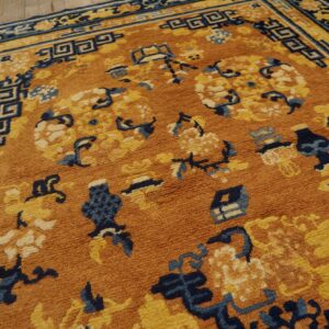 High-pile rug in rust orange, navy blue, and yellow with complex floral and fretwork patterns on wood floor.