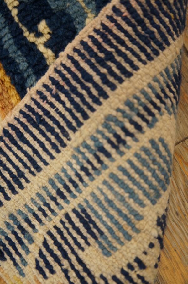 Folded rug detail shows a low pile cream ground with geometric dark and light blue dashes.