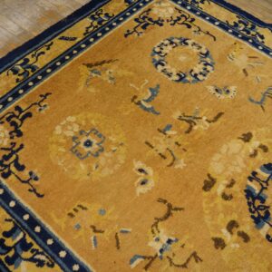 Camel rug featuring dark blue borders and circular floral medallions rests on rustic wood flooring.