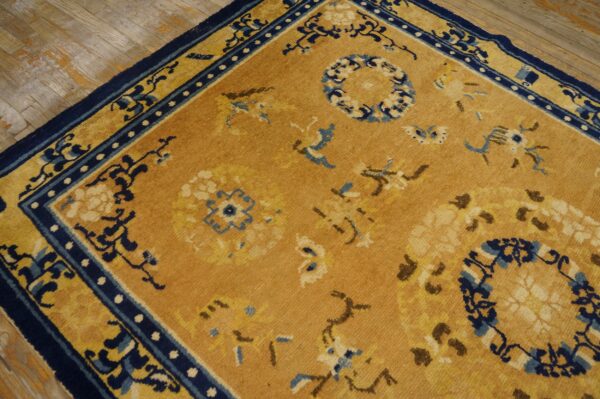 Camel rug featuring dark blue borders and circular floral medallions rests on rustic wood flooring.