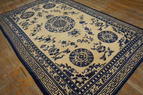 Blue and cream woven rug featuring medallions and elaborate geometric borders on rustic wood flooring.