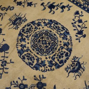 Cream rug featuring a detailed blue medallion, stylized vines, and a blue key pattern border.