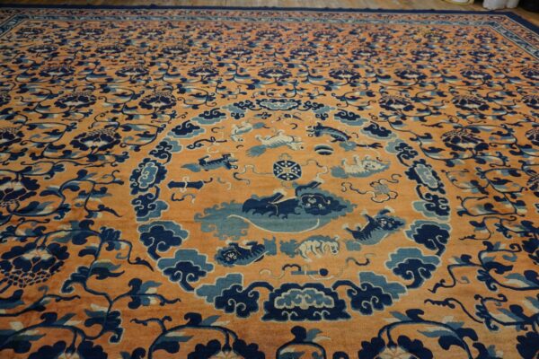 Orange field rug with extensive dark blue floral patterns and a light blue animal medallion.