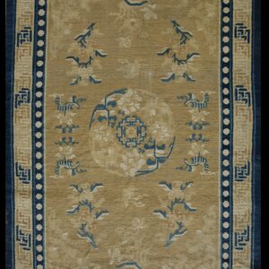 Low-pile Oriental rug with tan field, indigo medallion, and complex beige and blue fretwork borders.