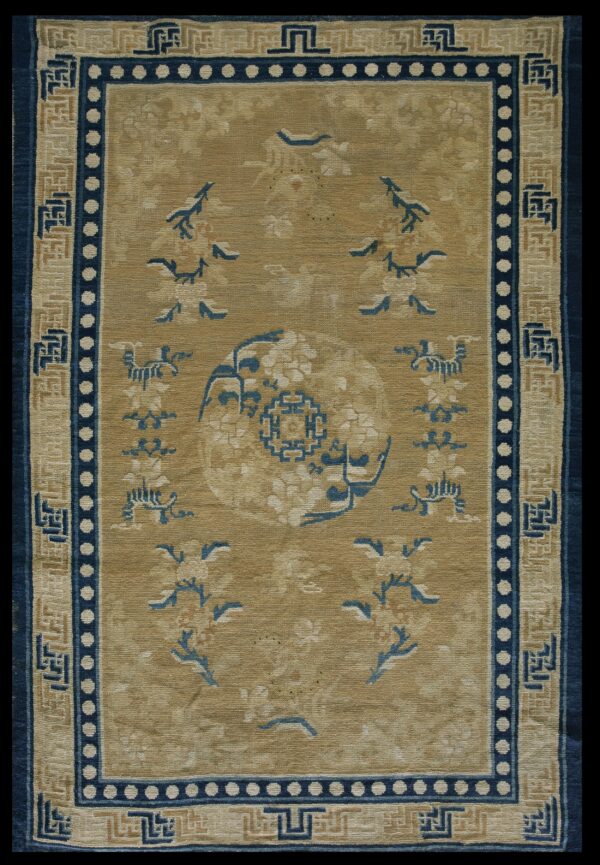 Low-pile oriental rug with tan field, indigo medallion, and complex beige and blue fretwork borders.