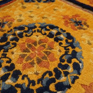 Textured gold rug featuring an ornate navy blue and burnt orange floral medallion and borders.