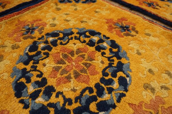 Textured gold rug featuring an ornate navy blue and burnt orange floral medallion and borders.