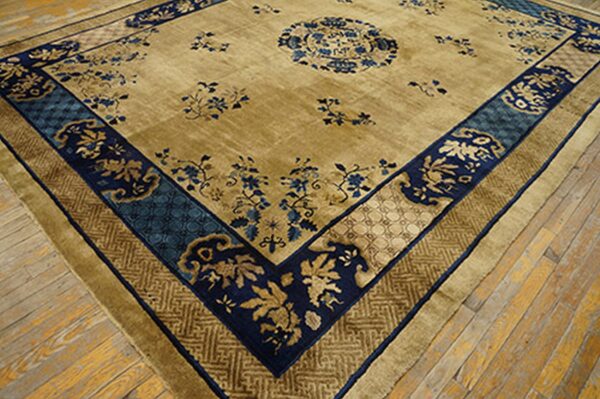 Angled view of a plush tan and blue rug with a central medallion laying on distressed wood floors.
