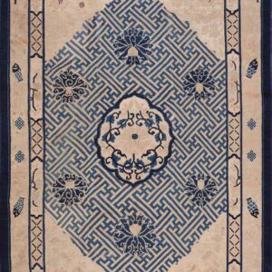 Beige rug featuring a large blue fretwork diamond motif surrounded by stylized florals and dark borders.