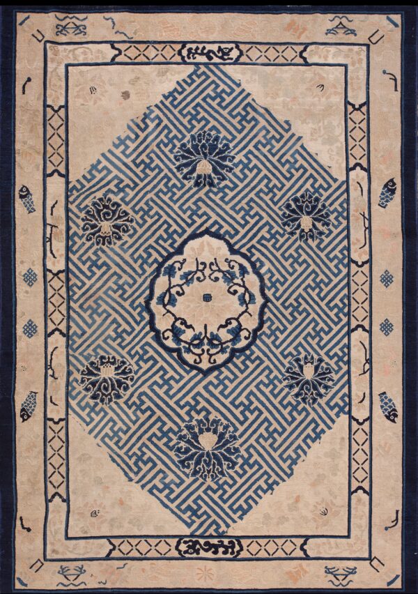 Beige rug featuring a large blue fretwork diamond motif surrounded by stylized florals and dark borders.