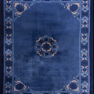Deep blue rug with an ornate medallion and geometric border pattern in light blue and tan accents.