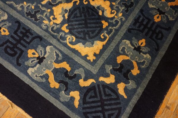 A deep blue rug featuring traditional gold and gray scrolling motifs and symbols rests on hardwood.