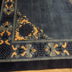 Deep blue rug with gold and gray symbolic border patterns visible on a light wood floor.
