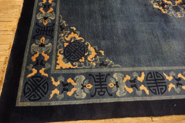 Deep blue rug with gold and gray symbolic border patterns visible on a light wood floor.