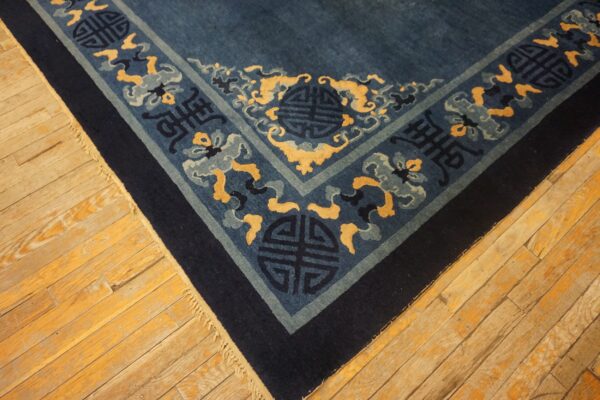 Blue rug corner with indigo, gold, and pale blue pattern rests on warm-toned wooden floors.