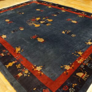 Blue rug with scattered gold and red floral motifs and a strong red border on wood flooring.