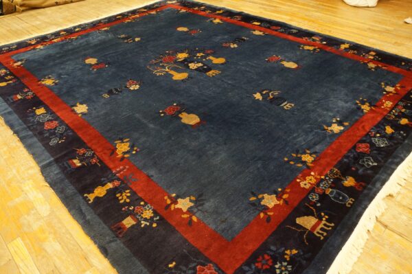 Blue rug with scattered gold and red floral motifs and a strong red border on wood flooring.