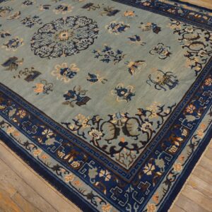A pale blue patterned rug with navy borders and central medallion rests on light wood planks.