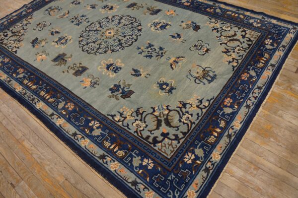 A pale blue patterned rug with navy borders and central medallion rests on light wood planks.