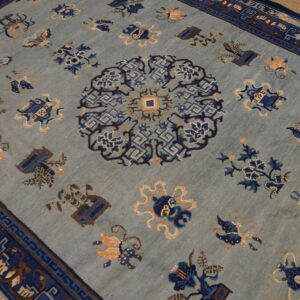 A light blue rug with a navy medallion and border, featuring scattered floral and symbolic motifs.