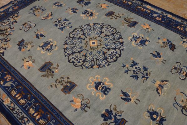 A light blue rug with a navy medallion and border, featuring scattered floral and symbolic motifs.