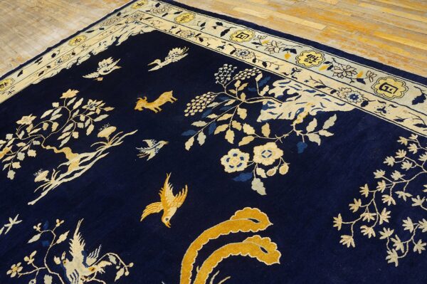 Dark blue rug featuring gold and cream birds, vines, and a goat, bordered by decorative yellow cartouche motifs.