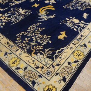 Navy blue rug with a detailed yellow and cream floral and bird pattern on light wood floors.