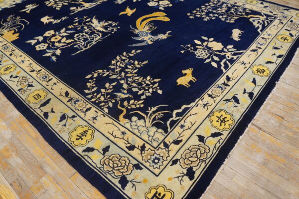 Navy blue rug with a detailed yellow and cream floral and bird pattern on light wood floors.