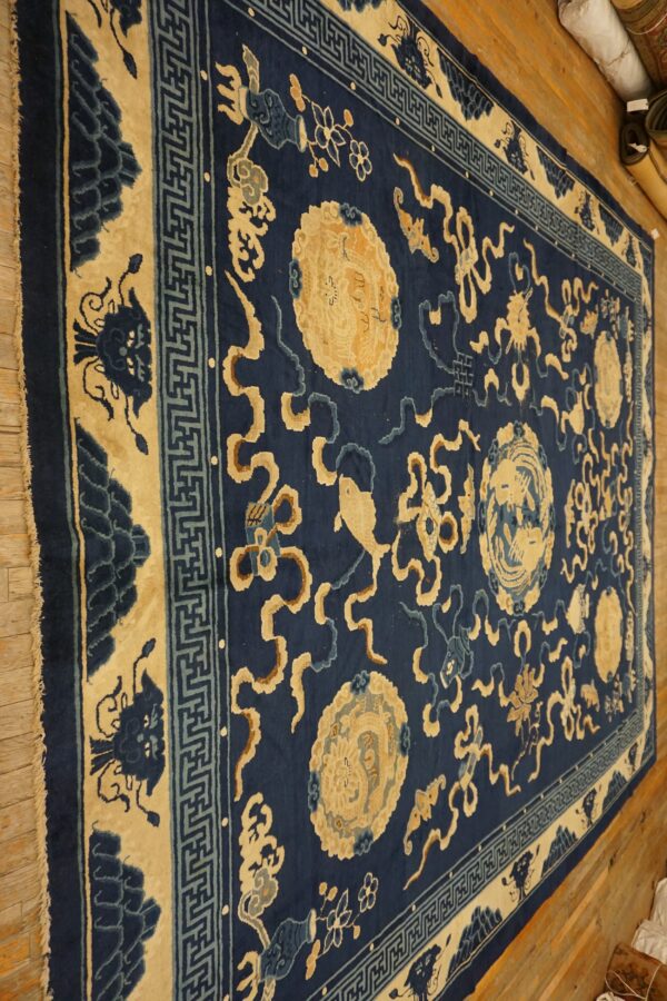 Deep blue rug with large beige medallions and detailed scrolling patterns sits on light wooden flooring.