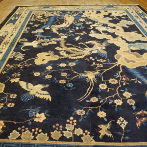 Dark blue rug featuring tan, blue, and gold scenic bird and floral motifs on wood flooring.