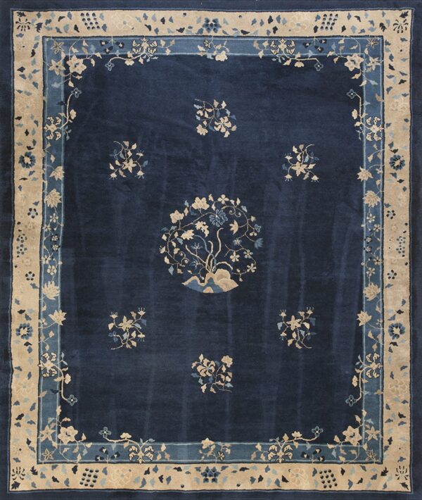 Dark blue rug with tan and light blue floral designs, centered medallion, and decorative wide borders.