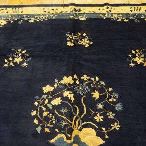 Navy blue rug with a central gold floral design and a wide border on light wood flooring.