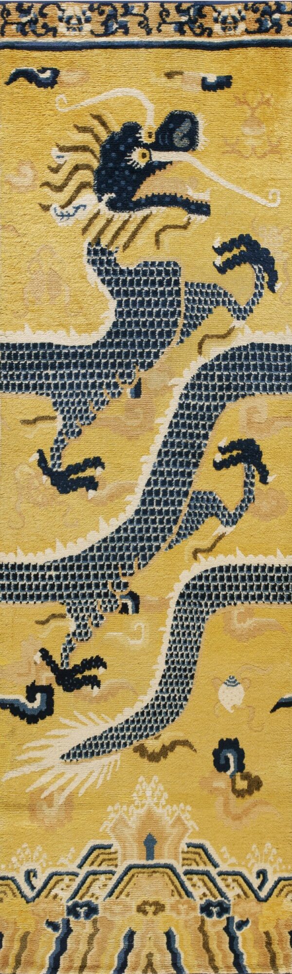 A vertical view of a gold and navy blue rug featuring a central stylized dragon pattern.