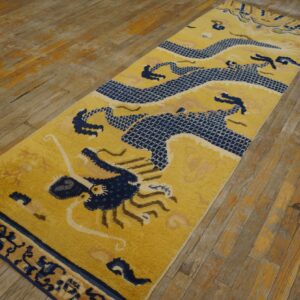 A yellow runner rug featuring a detailed navy blue dragon design rests on distressed wood flooring.