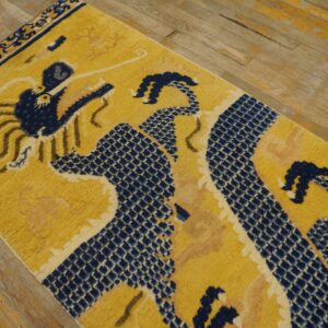 Yellow runner rug featuring a navy blue scaled dragon pattern and border on distressed wood flooring.