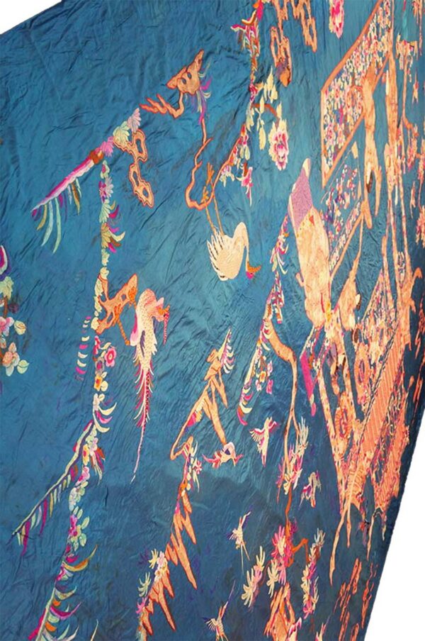 Crinkled deep teal textile embroidered with intricate orange and pink avian and floral designs.