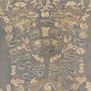 Muted blue rug featuring stylized tan dragons, clouds, and flowers bordered by beige striped panels.