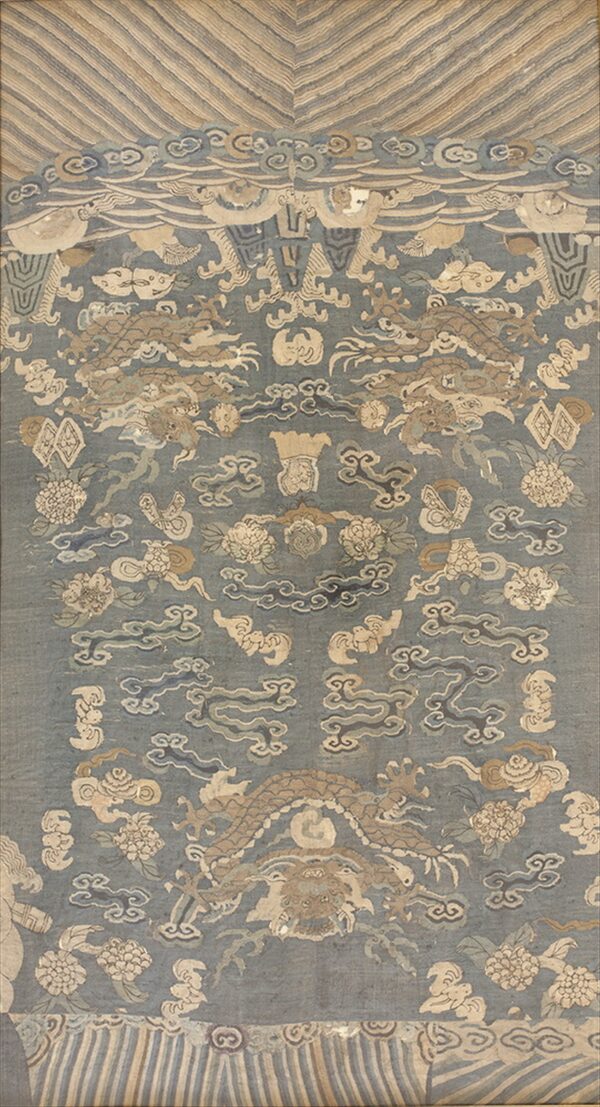 Muted blue rug featuring stylized tan dragons, clouds, and flowers bordered by beige striped panels.